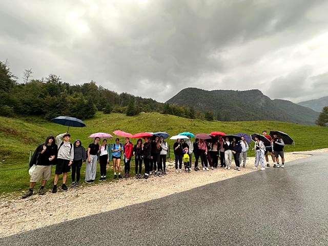 Dijaki na sprehodu kljub deževnemu dnevu. V rokah držijo odprte dežnike.