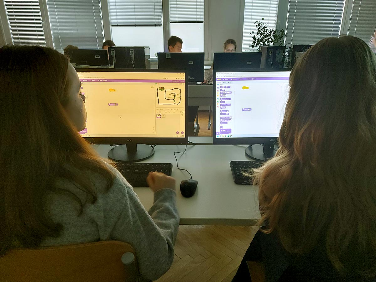 Učenki sedita za računalnikom in sestavljata program v scratchu.