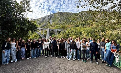 Velika skupina dijakov stoji na razgledni ploščadi, v ozadju je visok Solkanski most nad reko Sočo.