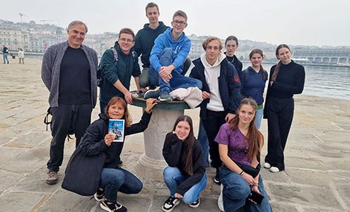 Devet dijakov, profesor in profesorica stojijo na kamnitem pomolu v Trstu.