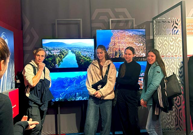 Štirje dijaki stojijo pred informativnimi zasloni v Multimedijskem informativnem centru slovenske narodne skupnosti v Italiji,