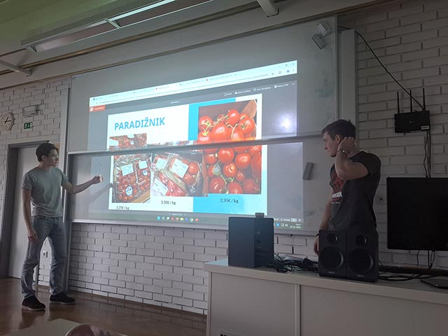 Dijaka stojita pri projekcijskem platnu v učilnici in predstavljata ugotovitve svoje raziskave o paradižnikih.