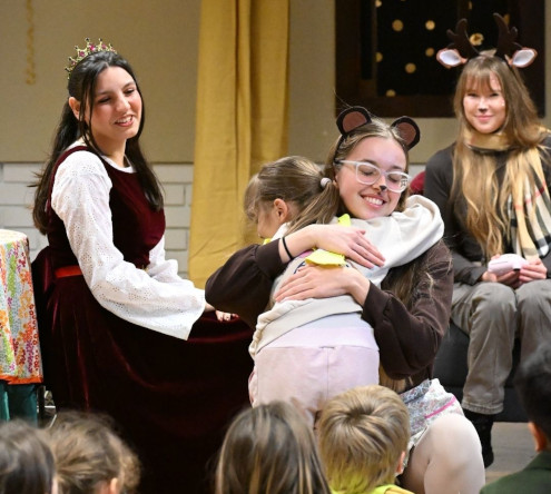 Deklica iz vrtca objema medvedko.