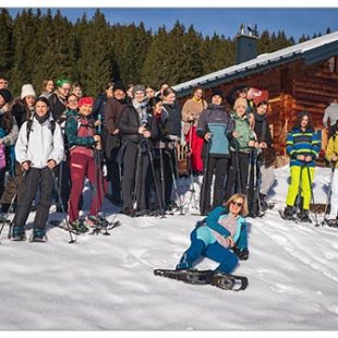 Večja skupina dijakov stoji na zasneženem pobočju, obsijanem s soncem. Na nogah imajo krplje, ki jim omogočajo lažjo hojo po snegu.