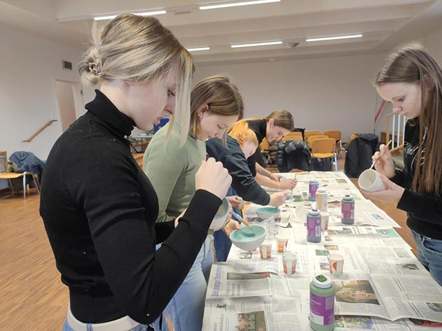 Dijaki sodelujejo v delavnici slikanja na keramiko.