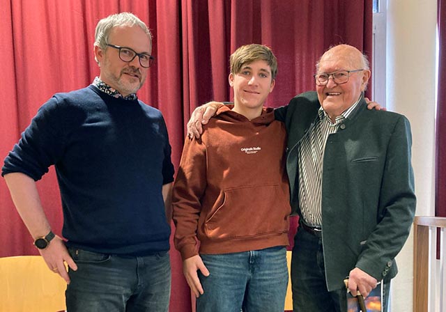 Dijak v družbi ravnatelja in starejšega gospoda. Dijak in gospod se z rokami objemata čez ramena.