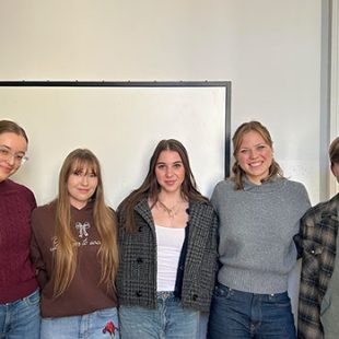 Štiri dijakinje in dijak stojijo v polkrogu v učilnici.