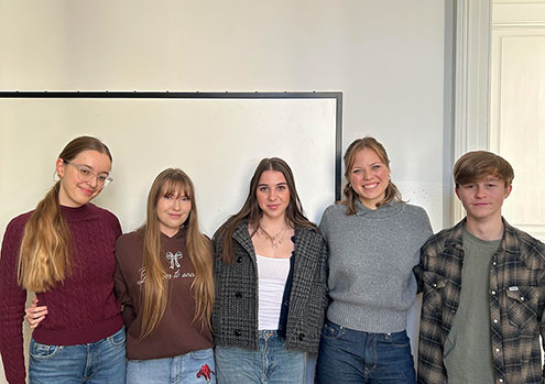 Štiri dijakinje in dijak stojijo v polkrogu v učilnici.