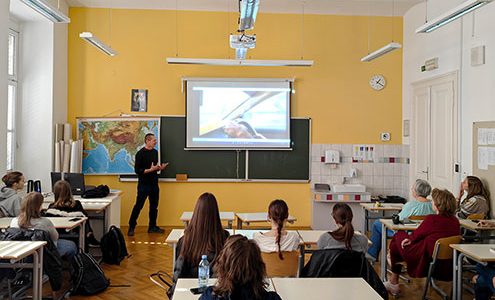 Potopisno predavanje o Afganistanu: Predavatelj živahno govori o fotografiji, ki je prikazana na projekcijskem platnu. Dijaki predavanje spremljajo iz šolskih klopi.