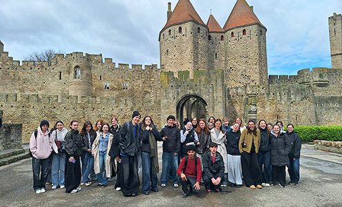 Skupina štiridesetih dijakov stoji pred obzidjem srednjeveškega mesta Carcassonne.