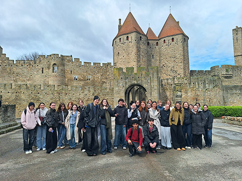 Skupina štiridesetih dijakov stoji pred obzidjem srednjeveškega mesta Carcassonne.