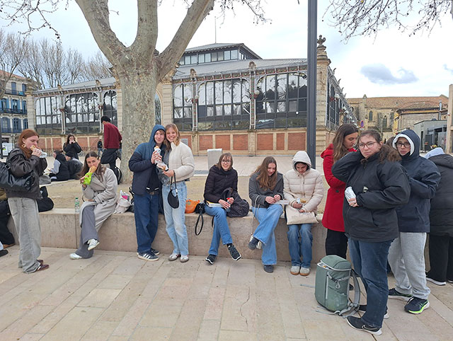 Dijaki med malico v mestu Narbonne. Sedijo na nizkem zidu. Zdi se, da je zelo mrzlo, saj so oblečeni v zimske jakne, nekateri imajo na glavah kapuce.