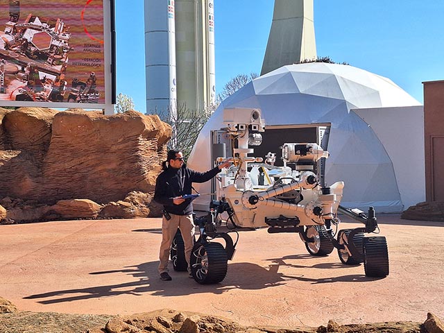 Na fotografiji je testno Nasino vozilo  rover, izdelano za raziskovanje površine Marsa. Poleg vozila stoji predavatelj, ki predstavlja funkcije vozila.
