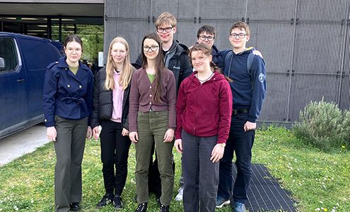 Sedem dijakov in dijakinj stoji na trati pred vhodom v Fakulteto za matematiko, naravoslovje in informacijske tehnologije.