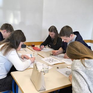 Tri dijakinje in dva dijaka sedijo za mizo in so zatopljeni v reševanje sudoka.