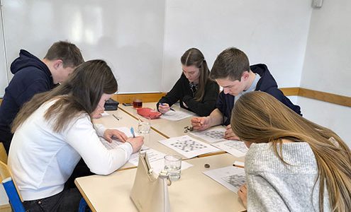 Tri dijakinje in dva dijaka sedijo za mizo in so zatopljeni v reševanje sudoka.