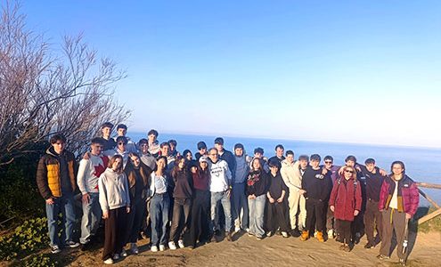 Na fotografiji je skupina približno 50 slovenskih in italijanskih dijakov, ki pozirajo za spominsko fotografijo na prostem. Stojijo na razgledni točki s pogledom na morje in nebom brez oblačka v ozadju. Oblečeni so v vsakdanja oblačila, kot so jakne, puloverji in hlače.