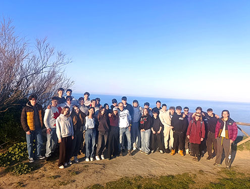 Na fotografiji je skupina približno 50 slovenskih in italijanskih dijakov, ki pozirajo za spominsko fotografijo na prostem. Stojijo na razgledni točki s pogledom na morje in nebom brez oblačka v ozadju. Oblečeni so v vsakdanja oblačila, kot so jakne, puloverji in hlače.