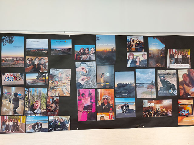 Črn pano na steni, na katerem je v obliki kolaža razstavljenih več različnih barvnih fotografij z napisi, ki prikazujejo utrinke z izmenjave.