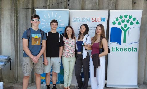Skupinska fotografija dijakov Gimnazije Ledina z mentorico na zaključni prireditvi projekta Krožnost je naša priložnost. V vrsti stojijo pred panojem z znakom Ekošole.