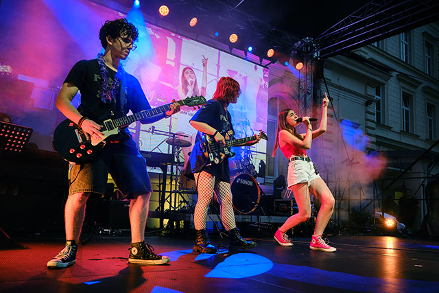 Ledinski rock band z električno kitaro, bas kitaro in pevko med energičnim nastopom.