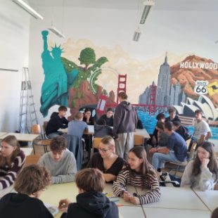 Dijaki v učilnici sedijo v dveh krogih ob mizah in se pogovarjajo o letošnji temi sleng.