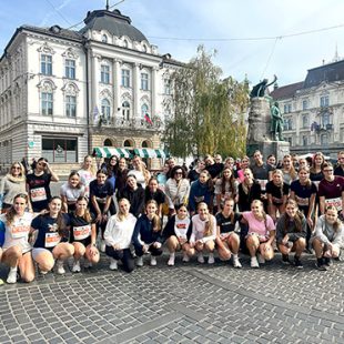 Velika skupina dijakinj in dijakov (skupaj okrog 60) je zbrana na Prešernovem trgu. Oblečeni so v tekaška oblačila, nekateri stojijo v več vrstah, drugi čepijo. So nasmejani.